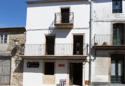 a white building with balconies on a street at Albergue San Anton in Melide