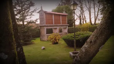 a stone building with two large wheels next to a building at Casa de Barreiro in Teijeiro