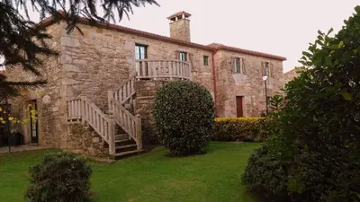 a table and a chair in front of a building at Casa de Barreiro in Teijeiro