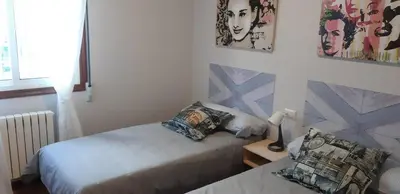 a small bedroom with two beds and a lamp at Parque da Ponte in Ourense