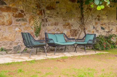 three green chairs sitting next to a stone wall at CASA CON ENCANTO (o Refuxio) in Merza
