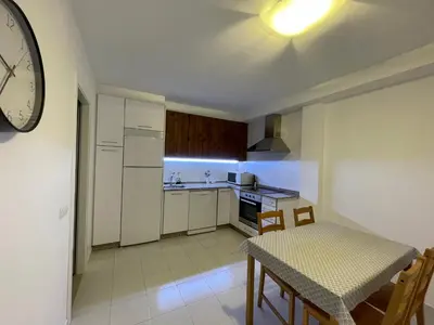 a kitchen with a table and a clock on the wall at ARZUAWAY in Arzúa