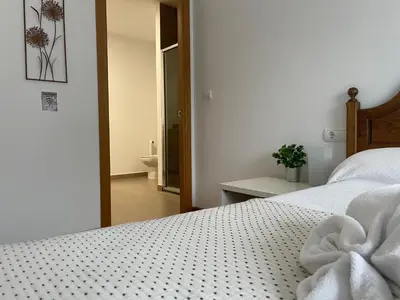 a bedroom with a bed with white sheets and a bathroom at ARZUAWAY in Arzúa
