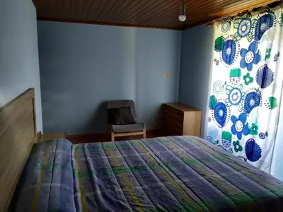 a bedroom with a bed and a chair and a window at Casa Xancin in Ribadeo