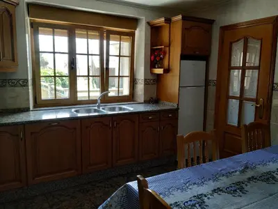 a kitchen with wooden cabinets and a sink and a window at Casa Xancin in Ribadeo