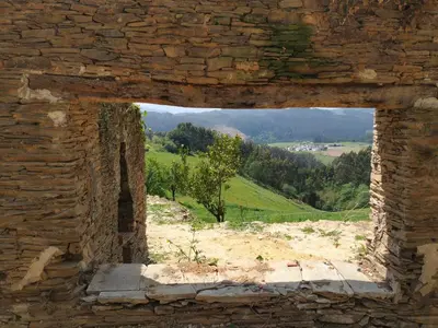 a window in a brick wall with a view of a field at Casa Xancin in Ribadeo