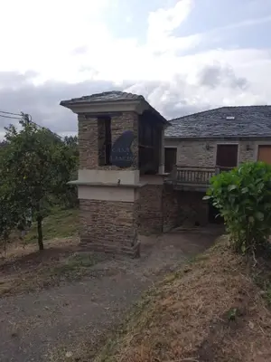 a stone house with a chimney and a porch at Casa Xancin in Ribadeo