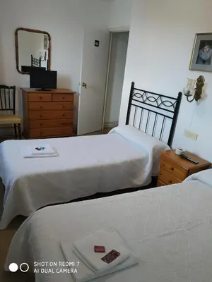a bedroom with two beds and a dresser and a mirror at Hostal padornelo in Mondoñedo
