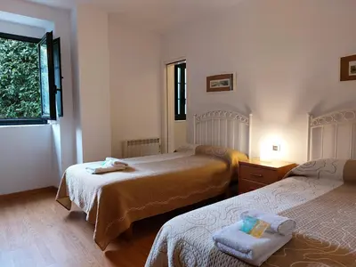 a bedroom with two beds and a window at Hospedería Externa del Monasterio in Samos