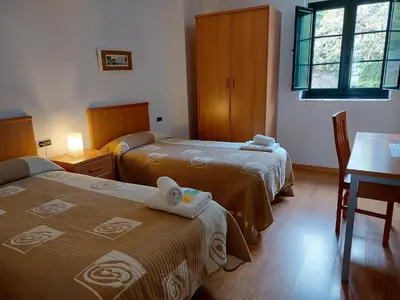 a hotel room with two beds and a table and a desk at Hospedería Externa del Monasterio in Samos
