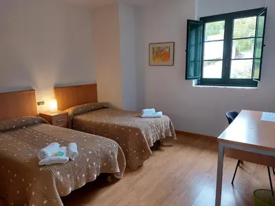 a hotel room with two beds and a window at Hospedería Externa del Monasterio in Samos