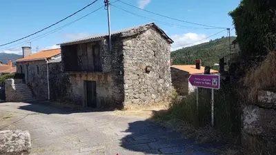 a small stone building with a sign in front of it at O POMAR VELLO in Pontevedra