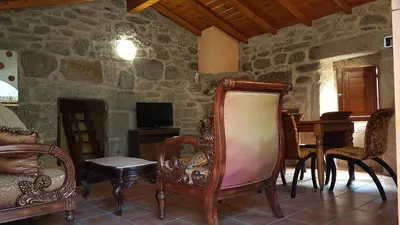 a living room with chairs and a stone wall at O POMAR VELLO in Pontevedra