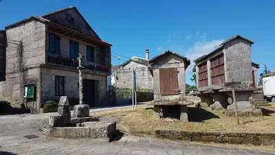 an old building with a cross in front of a church at O POMAR VELLO in Pontevedra