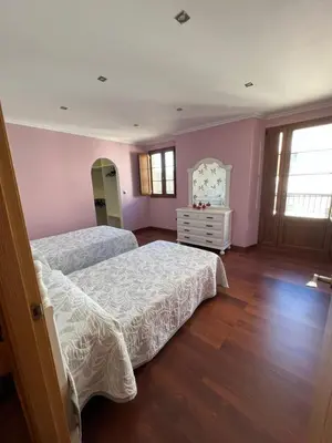 two beds in a room with pink walls and wooden floors at Apartamento Vila O Valadouro 2 in O Valadouro