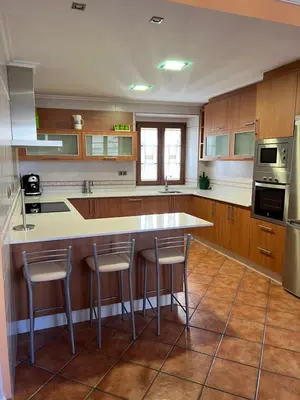 a kitchen with wooden cabinets and a island with bar stools at Apartamento Vila O Valadouro 2 in O Valadouro