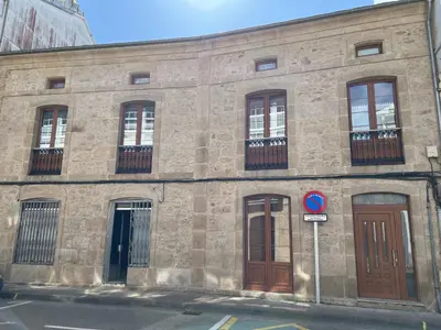 an old stone building with windows and doors on a street at Apartamento Vila O Valadouro 2 in O Valadouro