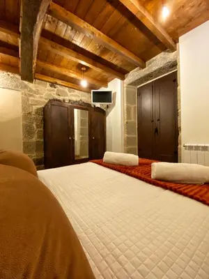 a large bedroom with a large white bed and a tv at Casa do Veiga in Chantada