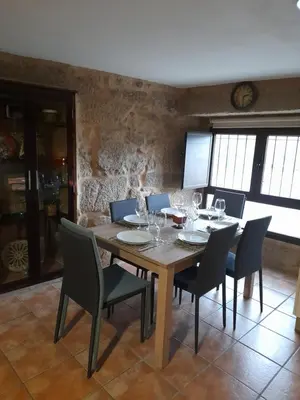 a dining room with a wooden table and chairs at O fogar da musiña in Maside
