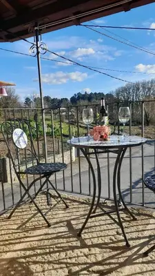 a table with two chairs and wine glasses on a porch at O fogar da musiña in Maside