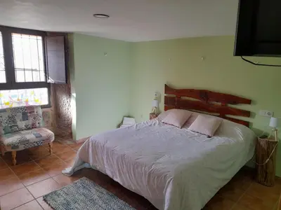 a bedroom with a large bed and a chair at O fogar da musiña in Maside