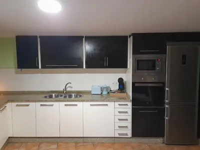 a kitchen with white cabinets and black appliances at O fogar da musiña in Maside
