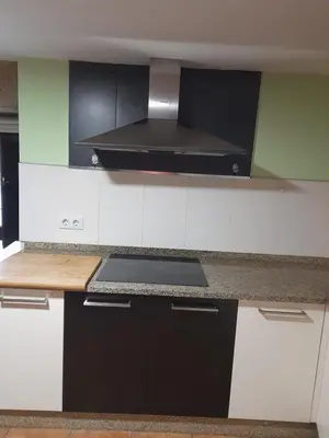 a kitchen with black and white cabinets and a stove at O fogar da musiña in Maside