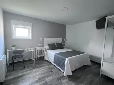 a bedroom with a bed and a table and a chair at HOSTAL CASA JULIO - Auto Check-in in Culleredo