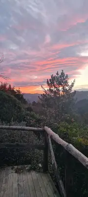 a wooden deck with a sunset in the background at Apartamentos Rurales El Bosque de las Viñas in Boal