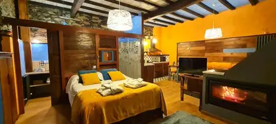 a bedroom with a bed with a fireplace and a tv at Apartamentos Rurales El Bosque de las Viñas in Boal