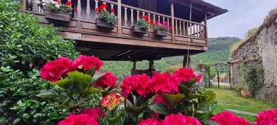 a balcony with red flowers in a garden at Apartamentos Rurales El Bosque de las Viñas in Boal