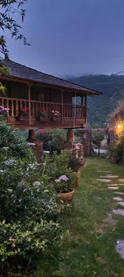a house with a porch with flowers in a yard at Apartamentos Rurales El Bosque de las Viñas in Boal
