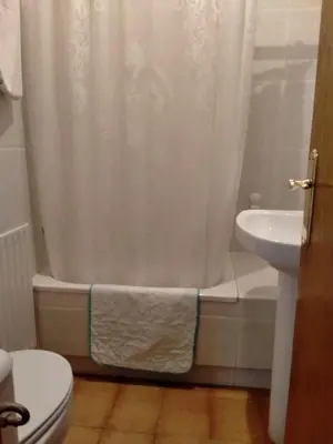 a bathroom with a white shower curtain and a sink at Casa da Fontiña in Seoane