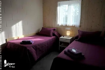 two beds in a room with purple sheets and a window at Albergue A Nave de Ferreira in Lugo