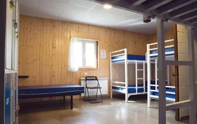 a room with bunk beds and a bench and a window at Albergue A Nave de Ferreira in Lugo