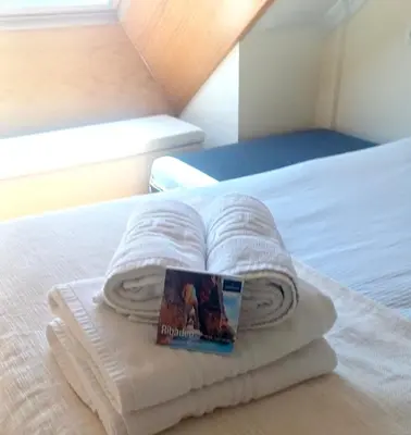 a stack of towels on a bed with a book at MODERNO PISO CON LA MEJOR TERRAZA DE RIBADEO Y VISTAS MARAVILLOSAS in Ribadeo