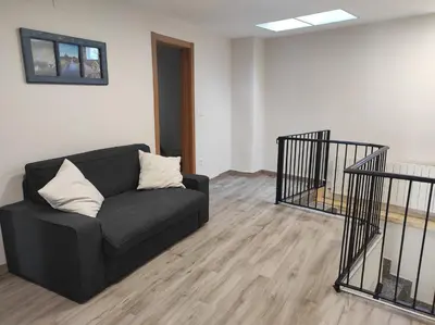 a living room with a black couch and wooden floors at Casa Galegos in Pantón