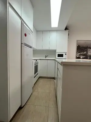 a white kitchen with white cabinets and appliances at Apartamento con terraza,2 min de la playa, Ares in Ares