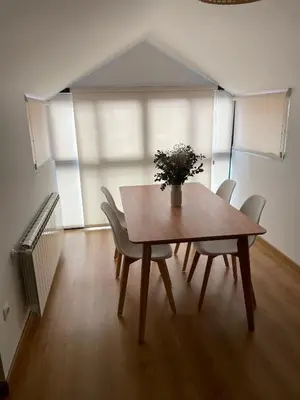 a dining room table with chairs and a vase of flowers on it at O Pequeno Rincón in Allariz