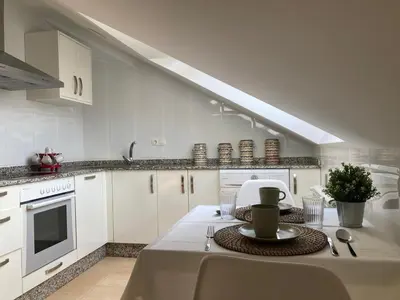 a kitchen with white cabinets and a table with a plate at O Pequeno Rincón in Allariz