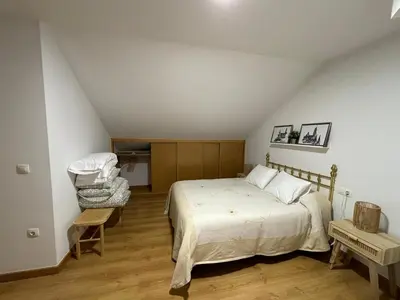 a bedroom with a bed and a chair in a attic at O Pequeno Rincón in Allariz