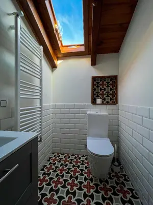a bathroom with a toilet and a tile floor at A Porteliña Casa Rural, entre viñedos y castaños in Ambas Aguas