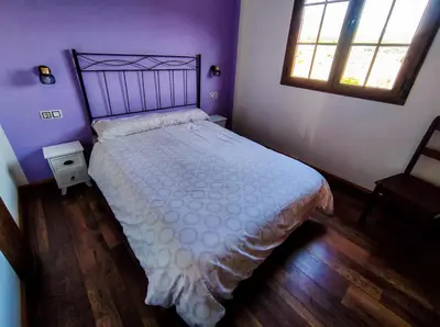 a bedroom with a bed with a white bedspread and a window at A Porteliña Casa Rural, entre viñedos y castaños in Ambas Aguas