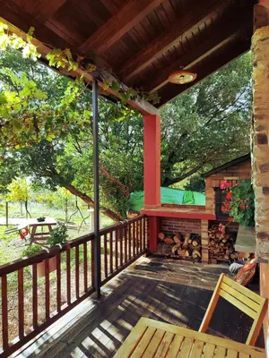 a deck with a fireplace and a table and chairs at A Porteliña Casa Rural, entre viñedos y castaños in Ambas Aguas