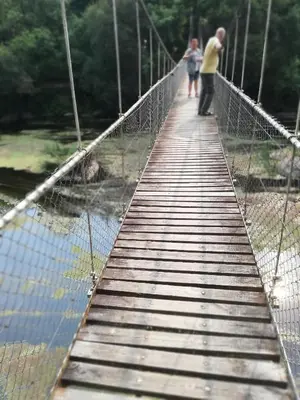 a man and woman walking across a suspension bridge at Apartamento turístico rural Casa Chaín in Lugo