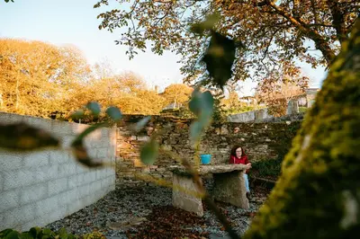 a woman sitting at a table next to a brick wall at Apartamento turístico rural Casa Chaín in Lugo
