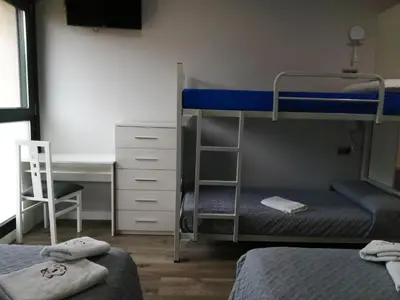 a bedroom with two bunk beds and a desk at PENSION PORTA SANTA in Baleira