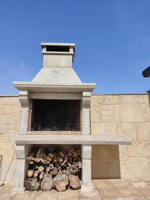 a stone fireplace with a pile of fire wood at A Chamiseiriña in Padrón