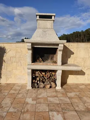 a stone fireplace with a pile of logs in it at A Chamiseiriña in Padrón