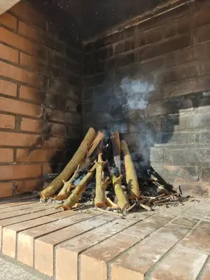 a fire in a brick fireplace with smoke at A Chamiseiriña in Padrón